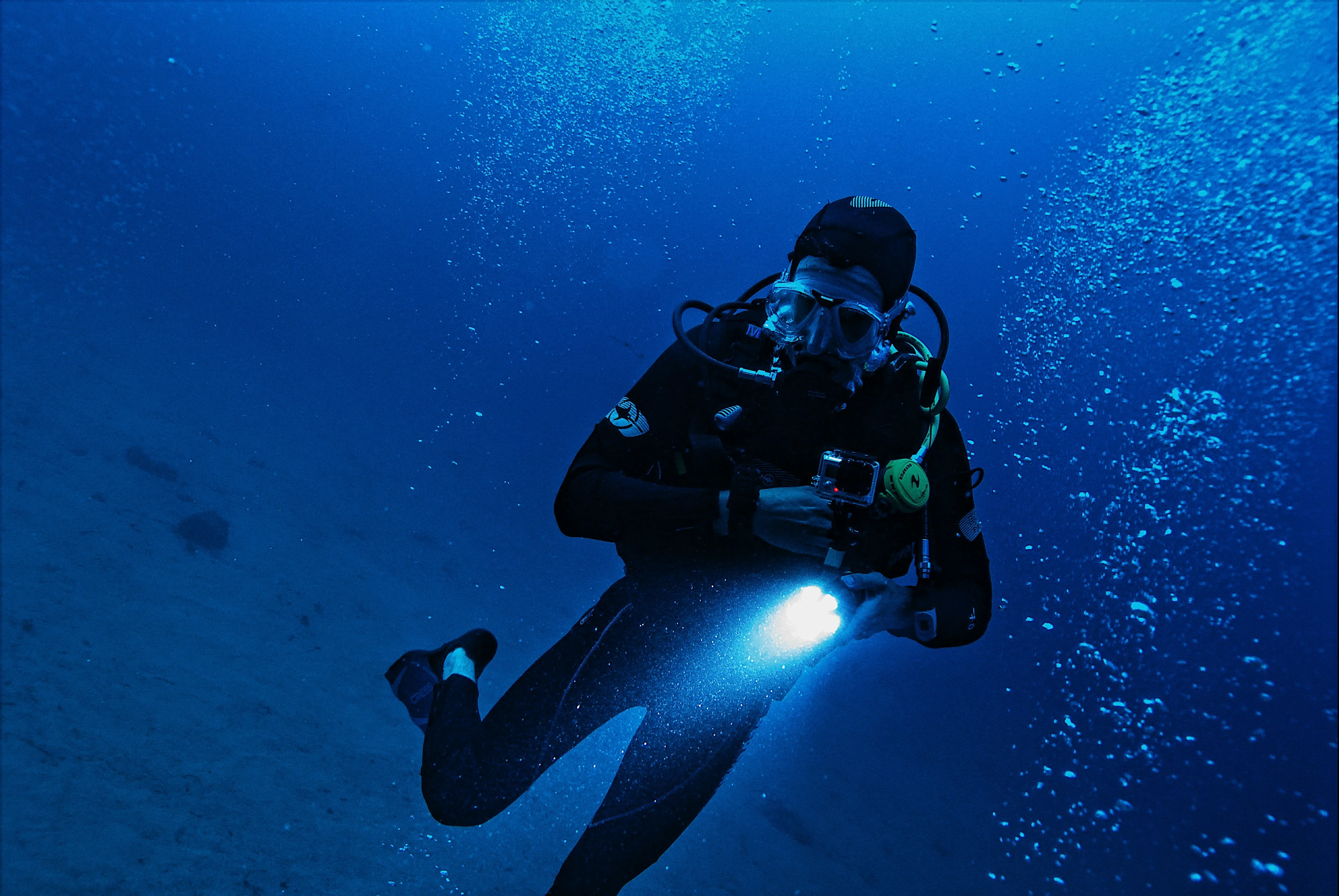 A scuba diver holds an illuminated handheld dive light underwater